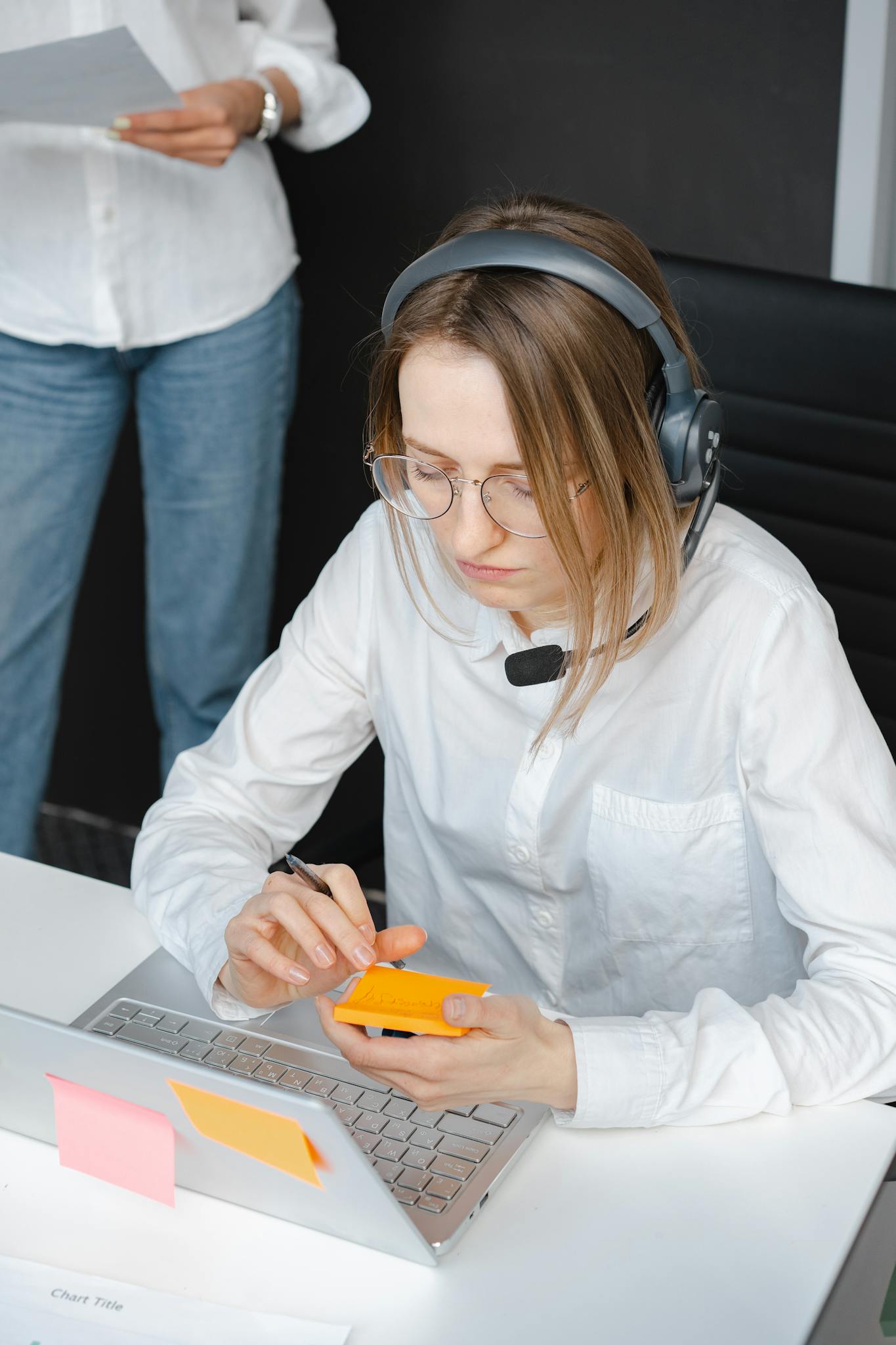 Focused professional woman wearing headphones and working with a laptop at her desk.